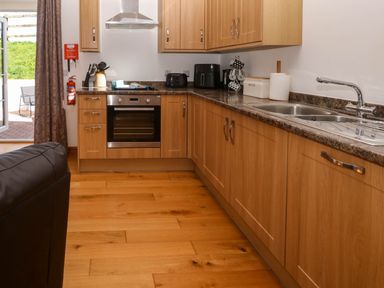 A kitchen with wooden cabinets stainless steel oven sink and countertop appliances at The Coach House in Hayle