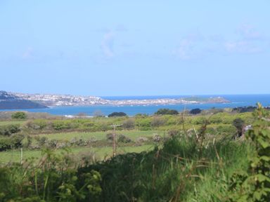 A coastal landscape with green fields and a town by the sea at The Coach House in Hayle