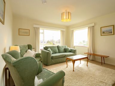 A living room with green armchairs a green sofa a wooden coffee table and a bench at Tegawelon in Llandanwg near Harlech