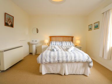 A bedroom with a double bed and bedside tables with lamps at Tegawelon in Llandanwg near Harlech