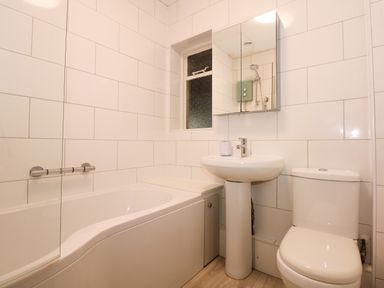 A bathroom with a bathtub a sink with a mirror cabinet and a toilet at Tegawelon in Llandanwg near Harlech