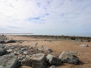 A rocky beach with sand and a cloudy sky at Tegawelon in Llandanwg near Harlech