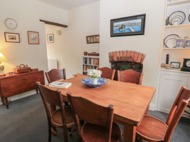 A dining room with wooden table and chairs a cupboard with plates and books at The Townhouse in Salisbury