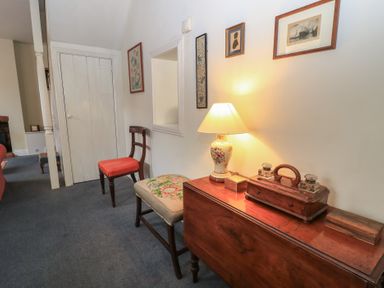 A hallway with a wooden table with a lamp and decorative items a chair and a bench on a carpeted floor at The Townhouse in Salisbury