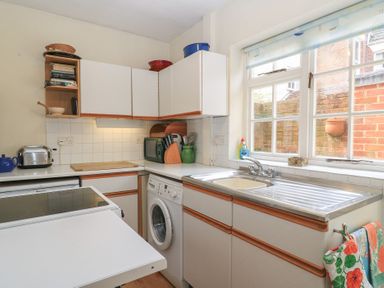 A kitchen with a washing machine a sink a window and white cabinets at The Townhouse in Salisbury