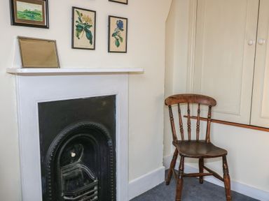 A corner with a black fireplace mantle a wooden chair and framed pictures on the wall at The Townhouse in Salisbury