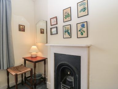 A corner of a room with a small wooden table and chair next to a fireplace with framed botanical prints on the wall at The Townhouse in Salisbury