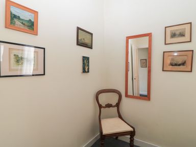A small corner with a wooden chair a wall mirror and framed pictures at The Townhouse in Salisbury