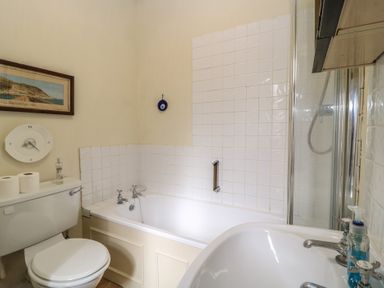 A bathroom with a toilet, bathtub with shower, sink, and a framed picture on the wall at The Townhouse in Salisbury