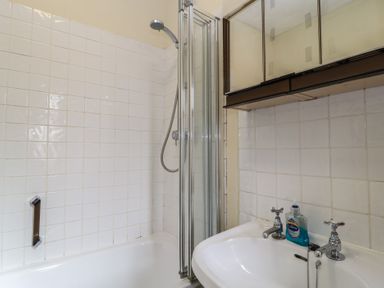 A bathroom with a bathtub shower combo sink with two taps and a soap dispenser at The Townhouse in Salisbury