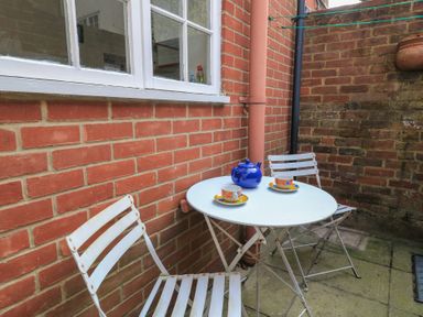 A small outdoor patio area with a white round table two white chairs a blue teapot and two cups at The Townhouse in Salisbury