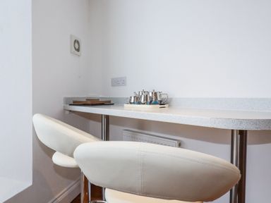 A kitchen counter with two white bar stools and a tray with metal teapots and cups at Trelowth Chapel in Polgooth
