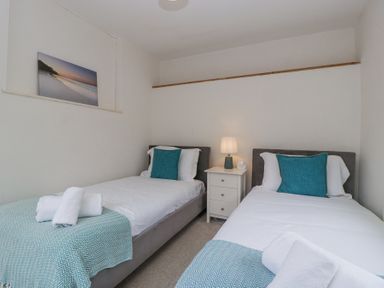 A bedroom with two single beds a bedside table and a lamp at Spring Cottage in Birdlip near Brockworth