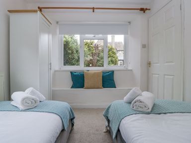 A bedroom with two beds each with rolled towels at Spring Cottage in Birdlip near Brockworth