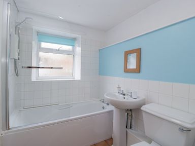 A bathroom with a bathtub shower combination sink toilet and a small mirror above the sink at Spring Cottage in Birdlip near Brockworth