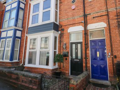 A brick house facade with black door number 26 and blue door number 27 with bay windows Seaside House Weymouth