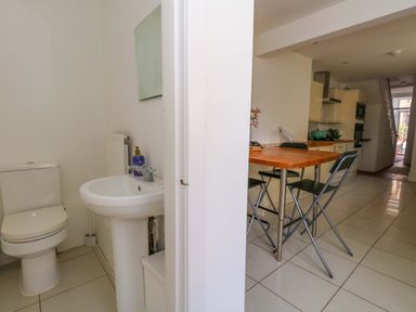 A bathroom with a sink and toilet beside a kitchen with a table at Weymouth Seaside House in Weymouth