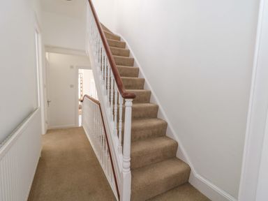 A hallway with stairs and a handrail at Weymouth Seaside House in Weymouth