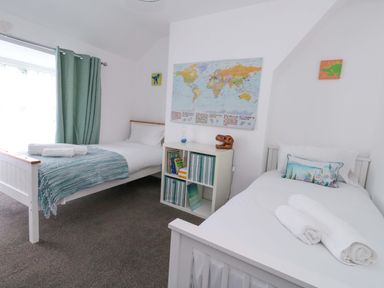 A bedroom with two beds and a world map on the wall at Weymouth Seaside House in Weymouth