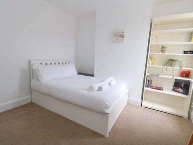 A bedroom with a bed and shelves at Weymouth Seaside House in Weymouth