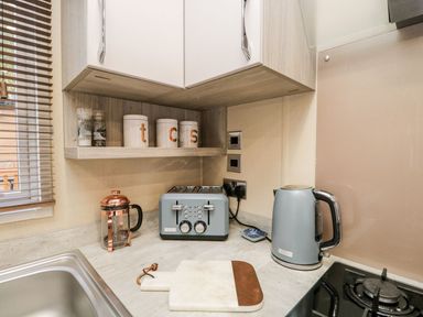 A kitchen countertop with a toaster kettle French press cutting board and containers on a shelf at Waters Reach White Cross Bay Holiday Park near Troutbeck Bridge
