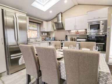 A kitchen with dining table and six chairs a refrigerator oven and microwave at Water's Reach White Cross Bay Holiday Park near Troutbeck Bridge