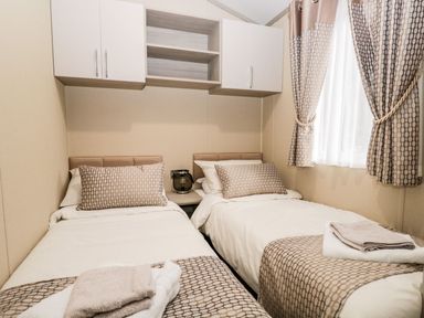 A bedroom with two single beds and towels on each bed at Water's Reach White Cross Bay Holiday Park near Troutbeck Bridge