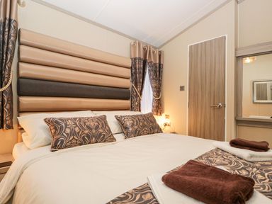 A bedroom with a bed having decorative pillows and towels placed on it at Water's Reach White Cross Bay Holiday Park near Troutbeck Bridge