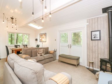 A living room with sofas a dining table and a wood burning stove at Serenity in Skiptory Howe 10 White Cross Bay near Windermere