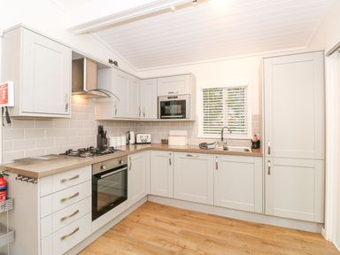A kitchen with cabinets a stove oven a microwave a sink and a window at Serenity Skiptory Howe 10 White Cross Bay near Windermere