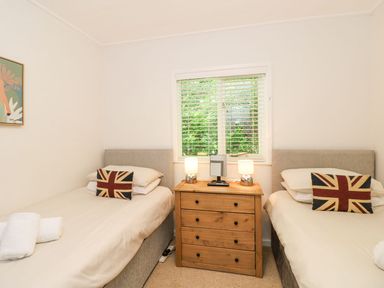 A bedroom with two single beds and a wooden dresser between them at Serenity Skiptory Howe 10 White Cross Bay near Windermere