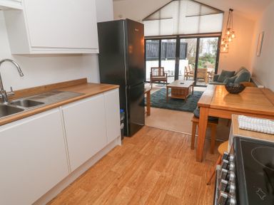 A kitchen with wooden countertops next to a dining table leading to a living area with large windows at Chy Benyngoth in Hayle