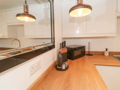 A kitchen countertop with a knife block salt and pepper shakers microwave and pendant lights at Chy Benyngoth in Hayle