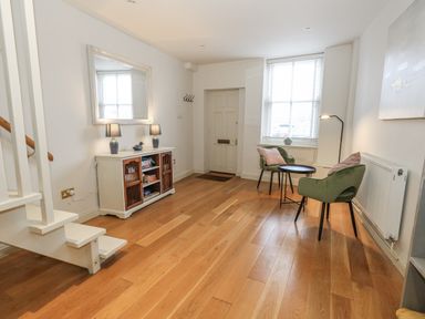 A hallway with a mirror, table, lamps, and a door at Harbourside in Weymouth