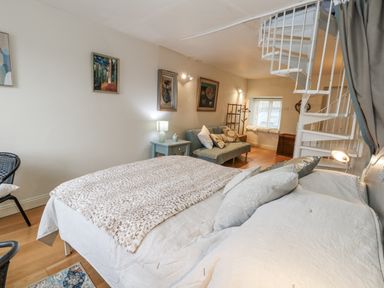 A bedroom with a bed, sofa, and staircase at Harbourside in Weymouth