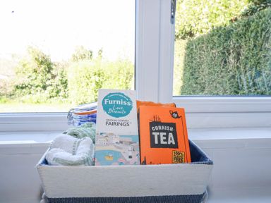 A basket with towels and boxes of Cornish tea and Furniss biscuits on a windowsill at Pennine in Veryan