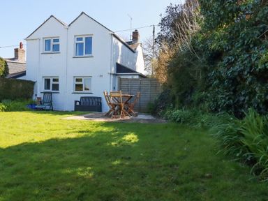 A backyard with green grass patio furniture and white two story house at Pennine in Veryan