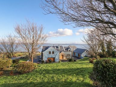 A view of a house with trees and a lake in the background at Ard Na Mara Drung near Quigley's Point, County Donegal