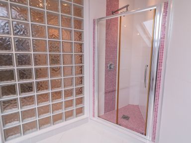 A shower enclosure with glass block wall and pink tiled floor at Ard Na Mara Drung near Quigley's Point, County Donegal