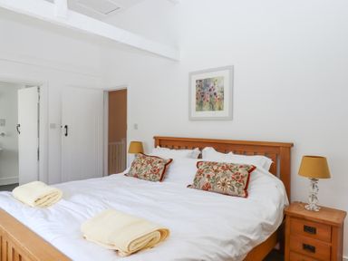 A bedroom with a wooden bed and bedside tables with lamps at 2 New Mill Cottages in North Bovey