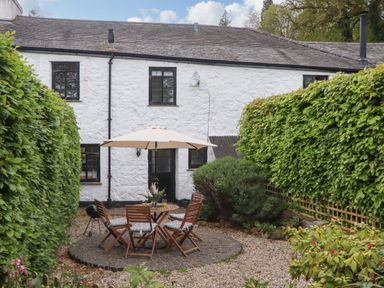 A garden with round table and chairs at 2 New Mill Cottages North Bovey