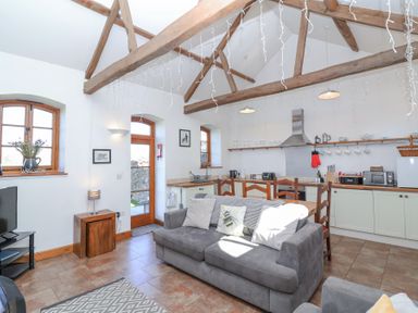 An open plan living room and kitchen with wooden beams on ceiling and grey sofa at The Yarde Annexe in Pen Elm near Taunton