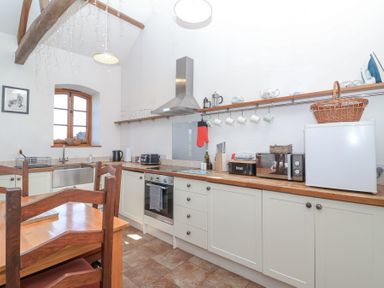 A kitchen with wooden countertops white cabinets a wooden dining table and chairs at The Yarde Annexe in Pen Elm near Taunton