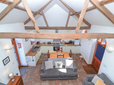 A kitchen and living area with wooden beams a dining table and sofas at The Yarde Annexe Pen Elm near Taunton