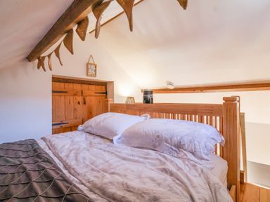 A bedroom with a wooden bed frame white floral bedding and wooden beam ceiling at The Yarde Annexe Pen Elm near Taunton