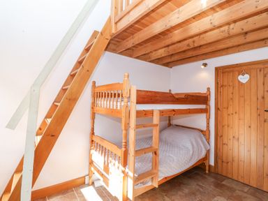 A bedroom with wooden bunk beds and a wooden staircase under a wooden beam ceiling at The Yarde Annexe in Pen Elm near Taunton