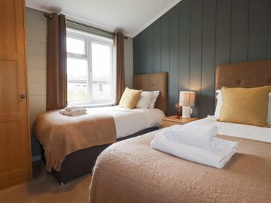 A bedroom with two single beds a window and a wardrobe at 6 Meadow Retreat in Dobwalls