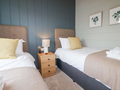 A bedroom with two single beds a nightstand lamp and framed plant prints on the wall at 6 Meadow Retreat in Dobwalls
