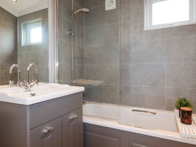 A bathroom with a sink cabinet and a bathtub with shower at 6 Meadow Retreat in Dobwalls