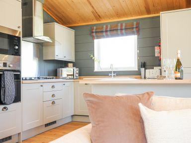 A kitchen area with white cabinets a stove oven microwave and a window above the sink at 17 Meadow Retreat in Dobwalls